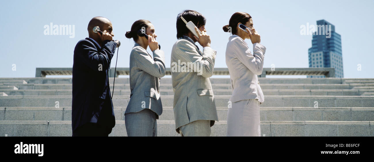 Männer und Frauen in Linie mit sukzessive weiter fortgeschrittenen Handys professionell gekleidet Stockfoto