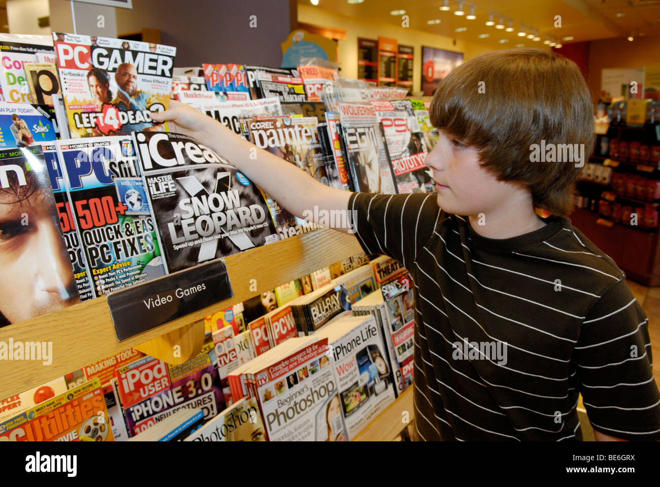 Junge (12-13) in Buchhandlung Blick auf Zeitschriften Stockfoto