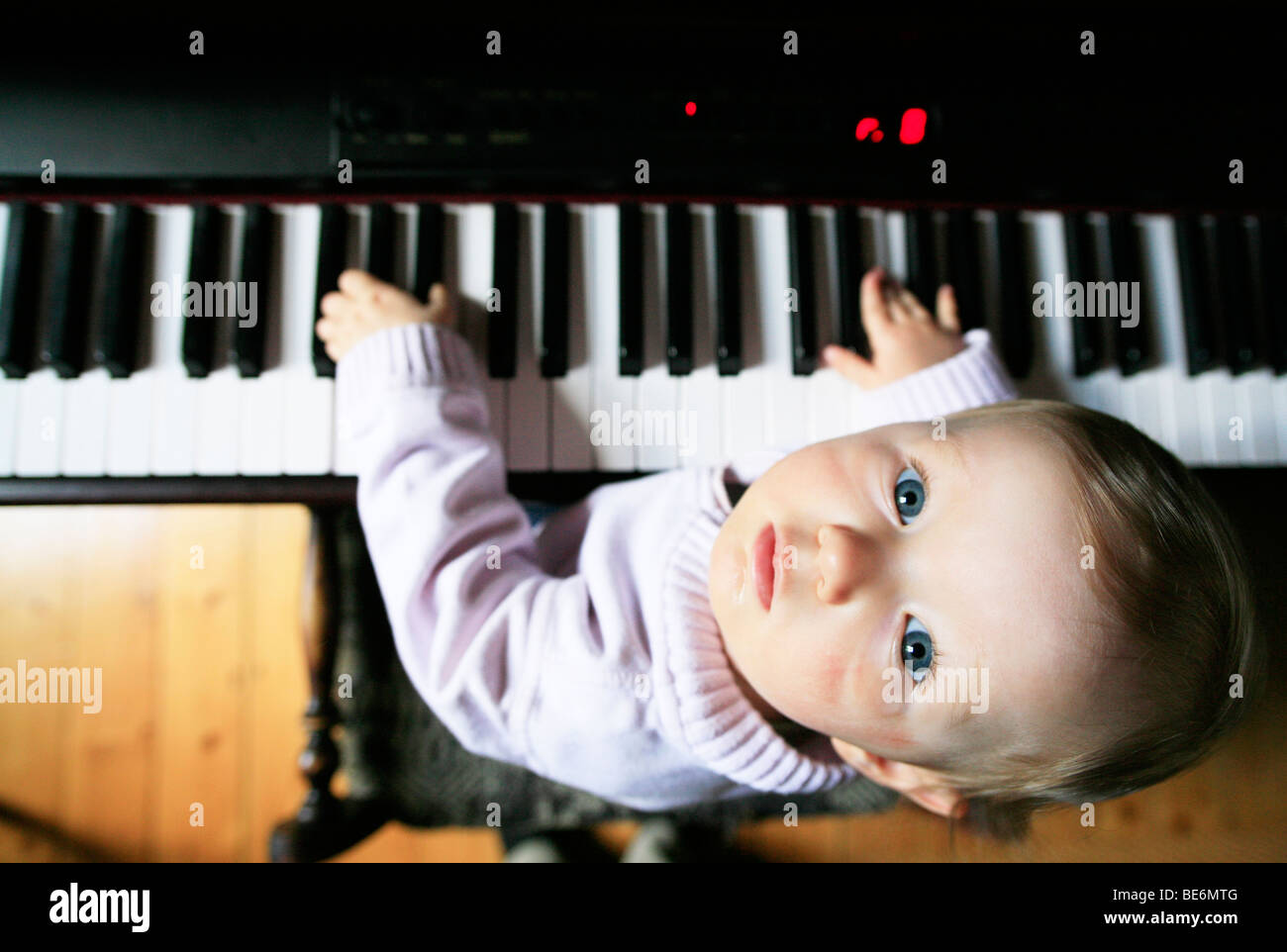 1 Jahr alt sitzt am Klavier Stockfoto