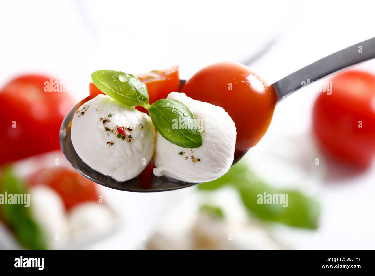 Mozzarellakugeln mit Tomaten und Basilikum auf einem Löffel Stockfoto