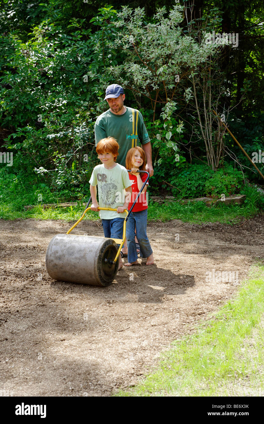 Familie im Garten, neuer Rasen, Rasen, Rasen, Rasen, Gartenwalze, Roll, Stockfoto