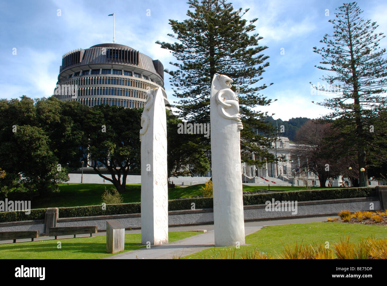 Bienenstock Neuseeland Parlament mit Maori, Pou Whenua oder Grenze Marker im Vordergrund. Stockfoto