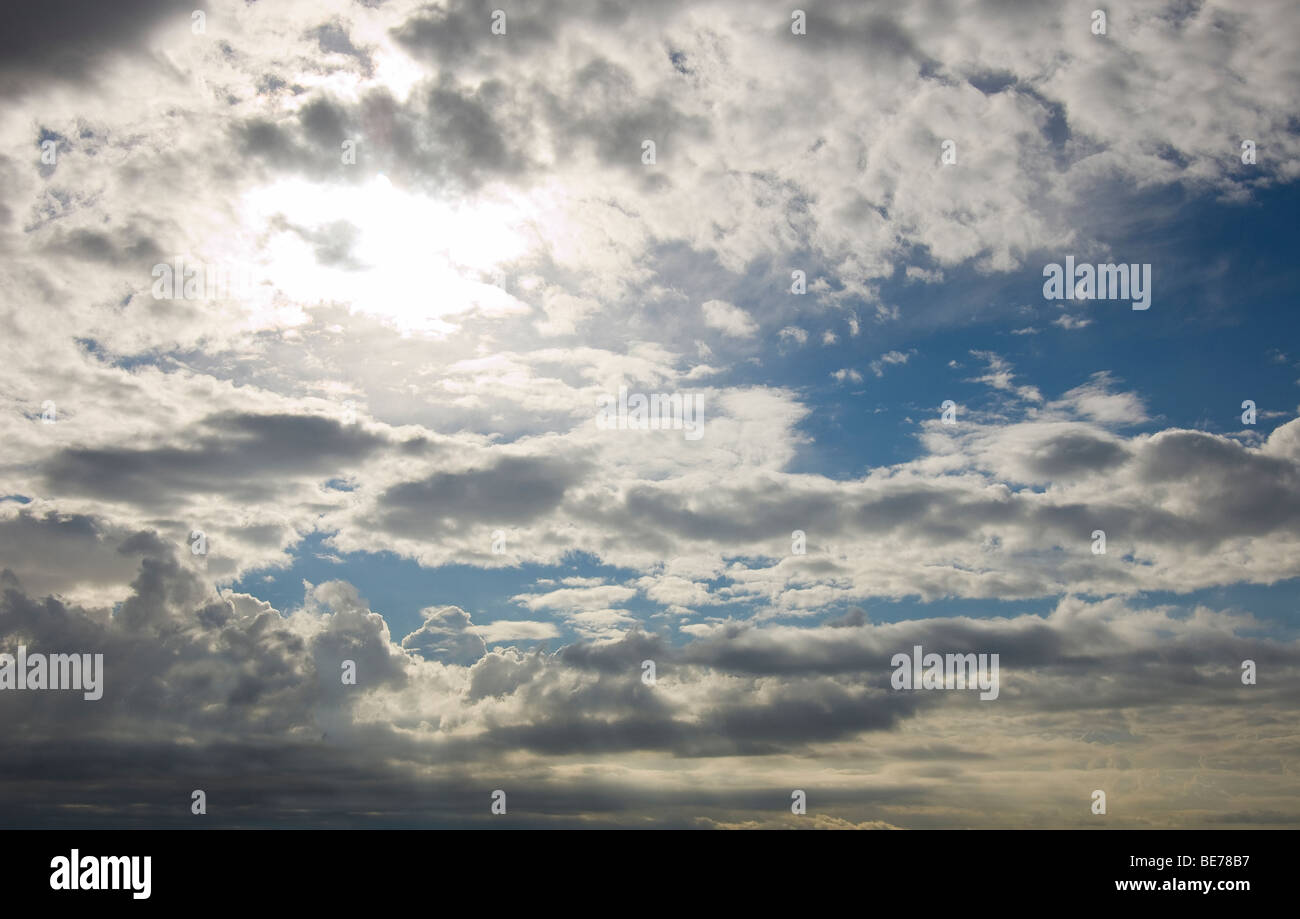 blaue bewölkter Himmel mit Sonne hinter Wolken Stockfoto