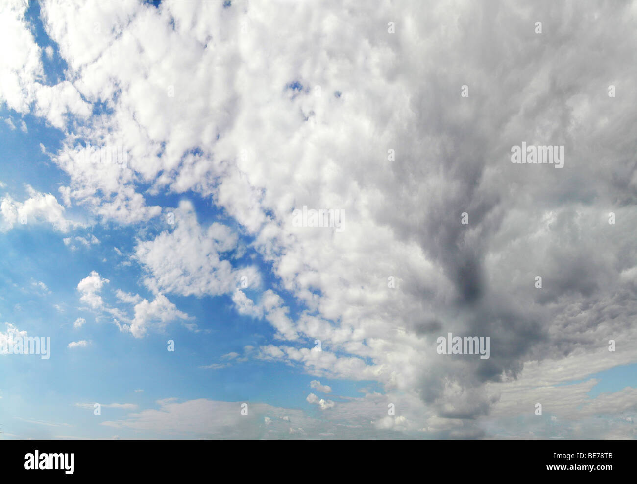 blauer Himmel mit großen weiß/grauen Wolken vorne Stockfoto