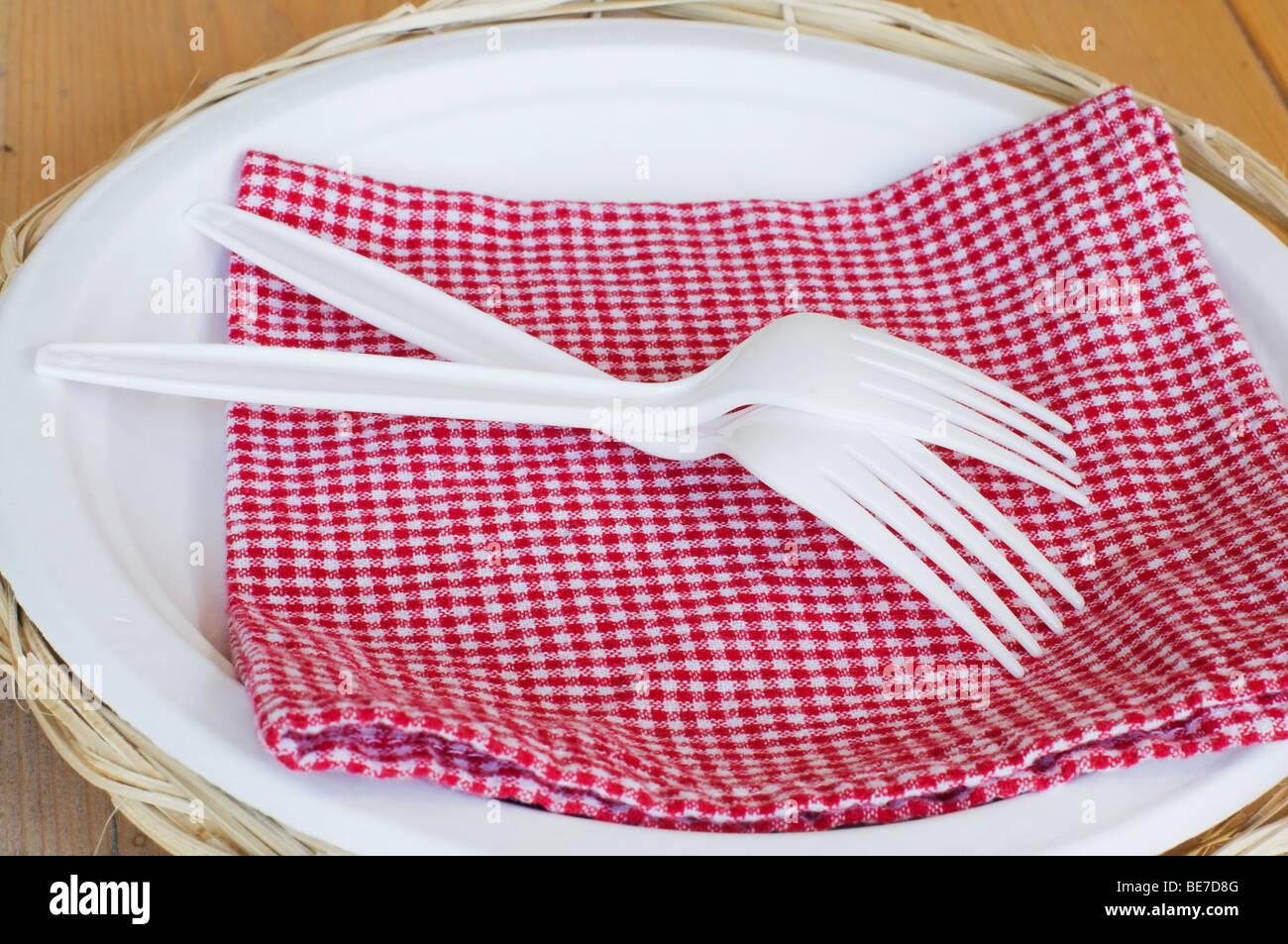 Nahaufnahme von zwei weißen Kunststoff-Gabeln, überprüft eine rote Serviette und einen Pappteller auf einem Korb. Stockfoto