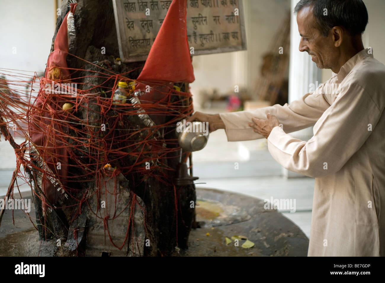 Ein Mann macht eine Opfergabe an die Götter auf einem Baum-Schrein in einem hinduistischen Tempel Janakpuri, New Delhi, Indien Stockfoto