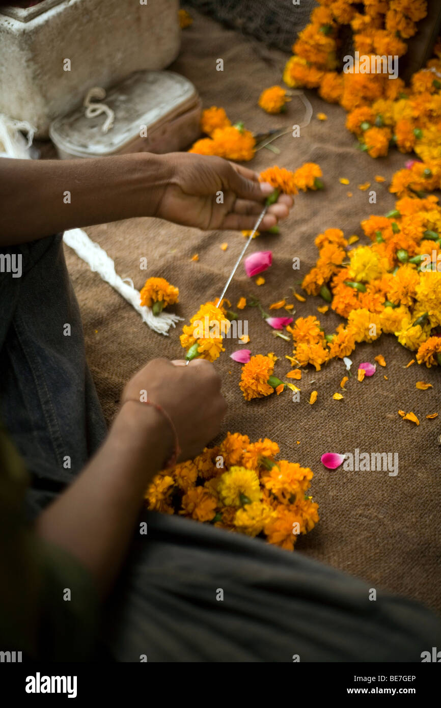 Ein Mann macht Girlanden aus Blumen anzubieten am Schrein in einem hinduistischen Tempel Janakpuri, New Delhi, Indien Stockfoto