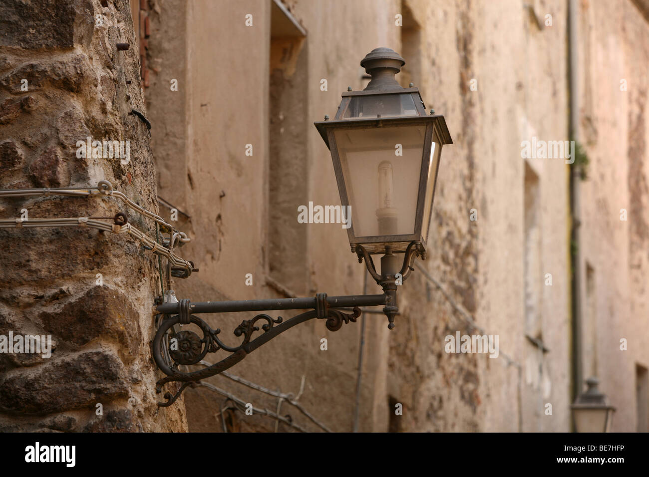 Eine alte Straßenlaterne an der zerbröckelnden Wand in Castelsardo, Sardinien befestigt Stockfoto
