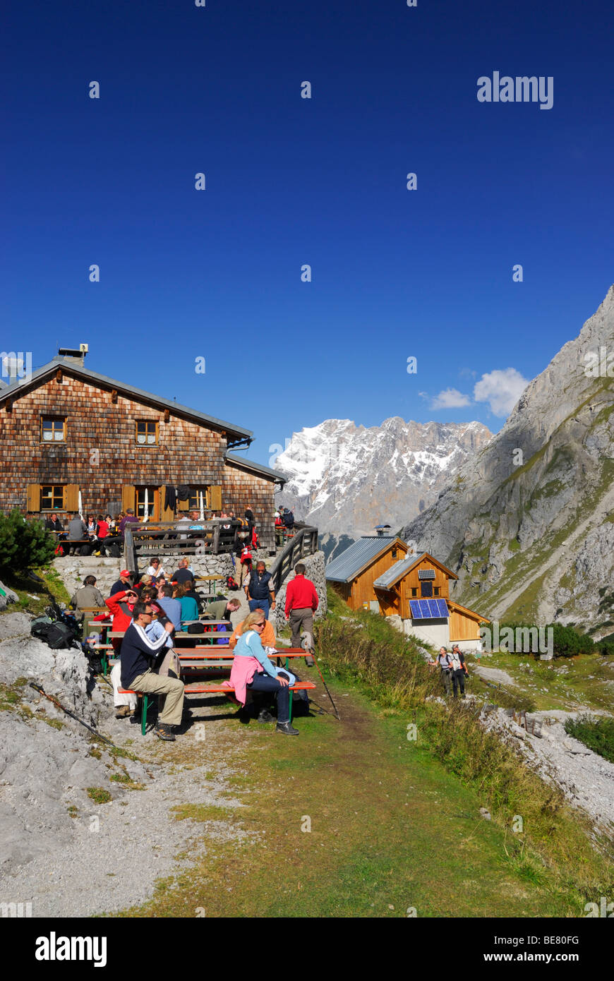 Wanderer ruht vor Hütte Coburger Hütte mit Blick auf Zugspitze, Mieminger Gebirge Bereich, Tirol Stockfoto