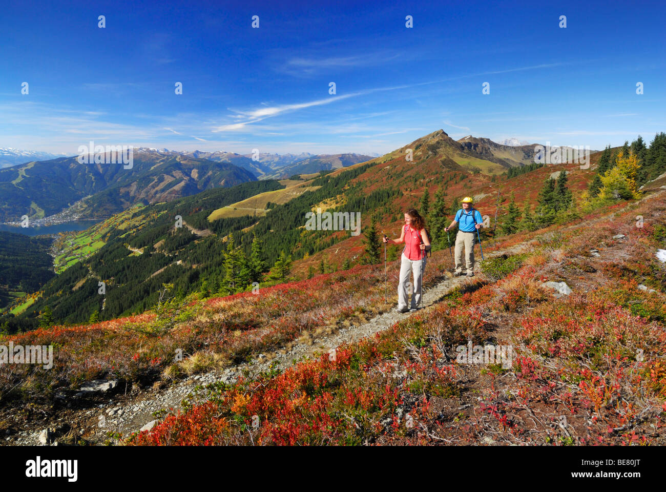 Paar Wandern auf Spuren am Hundstein mit Blick zum Dorf Zell am See, Schmittenhöhe und Schwalbenwand mit herbstlichen Farben der hu Stockfoto
