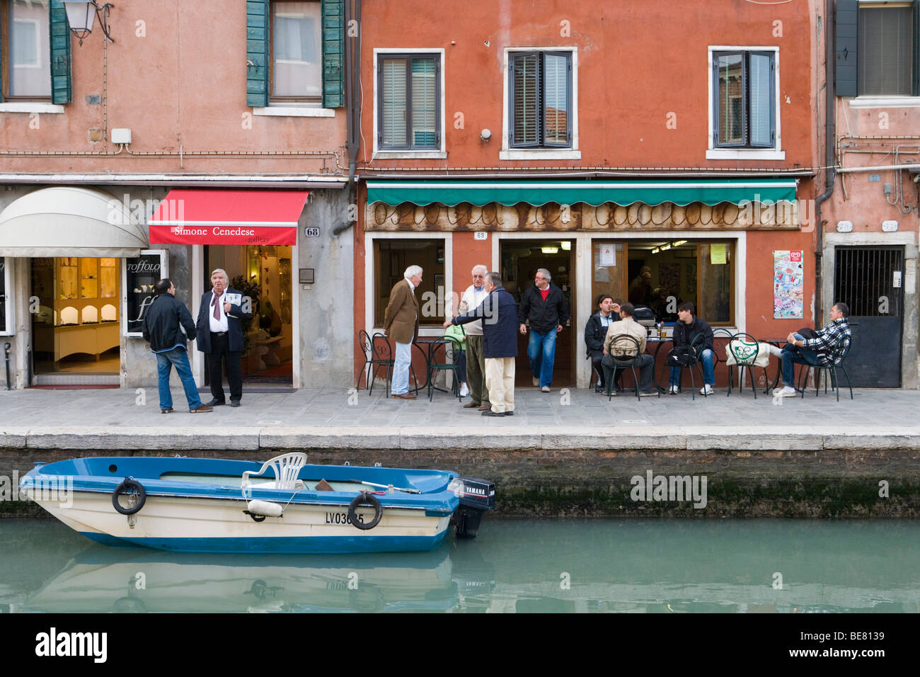 Männer im Gespräch vor einer Bar, Straßenszene am Rio dei Vetrai Kanal, Murano, Veneto, Italien Stockfoto