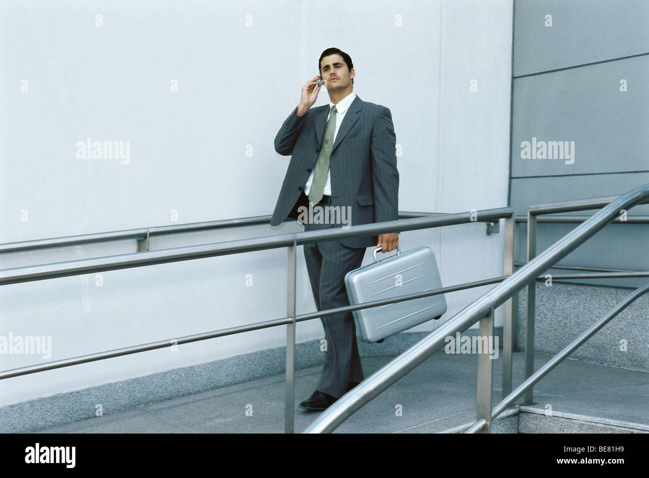 Geschäftsmann zu Fuß auf dem Bürgersteig mit Handy, mit Aktentasche Stockfoto