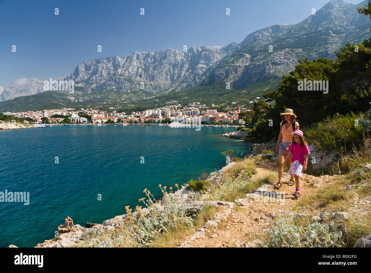 Frau und Kind zu Fuß unterwegs an der Küste in der Sonne, Blick auf Makarska, Dalmatien, Kroatien, Europa Stockfoto