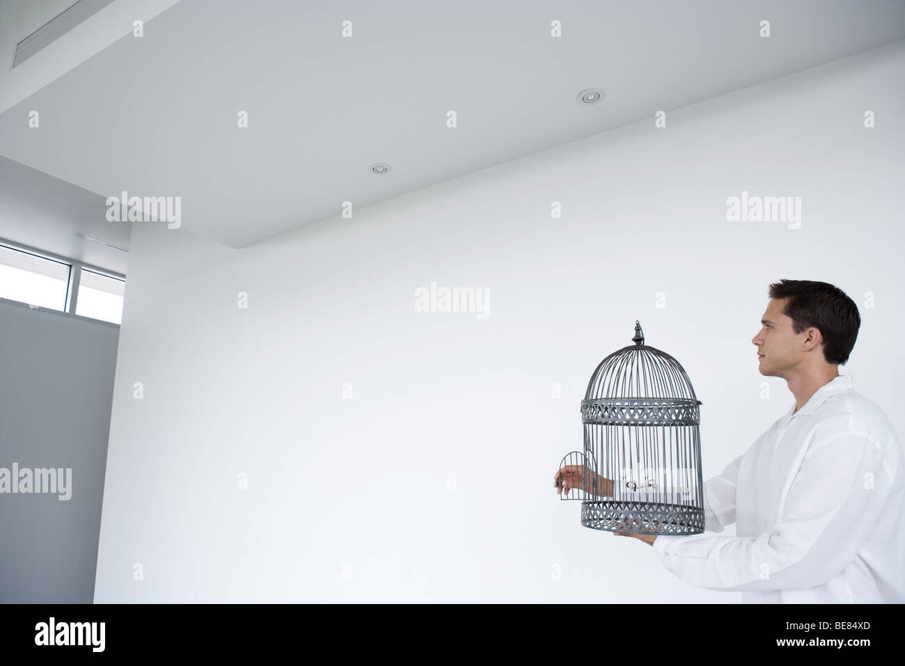 Mann mit leeren Vogelkäfig mit offener Tür, Seitenansicht Stockfoto