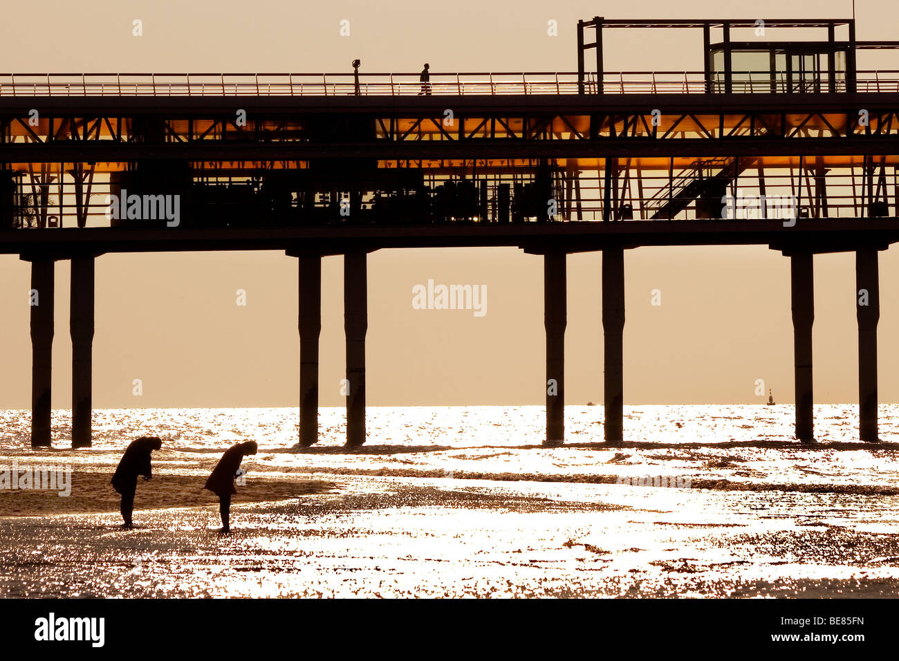 Twee Mensen in warmen Avondlicht Op Strang Bij Scheveningse Pier; Zwei Personen im warmen Abendlicht vor Scheveningen Pier Stockfoto