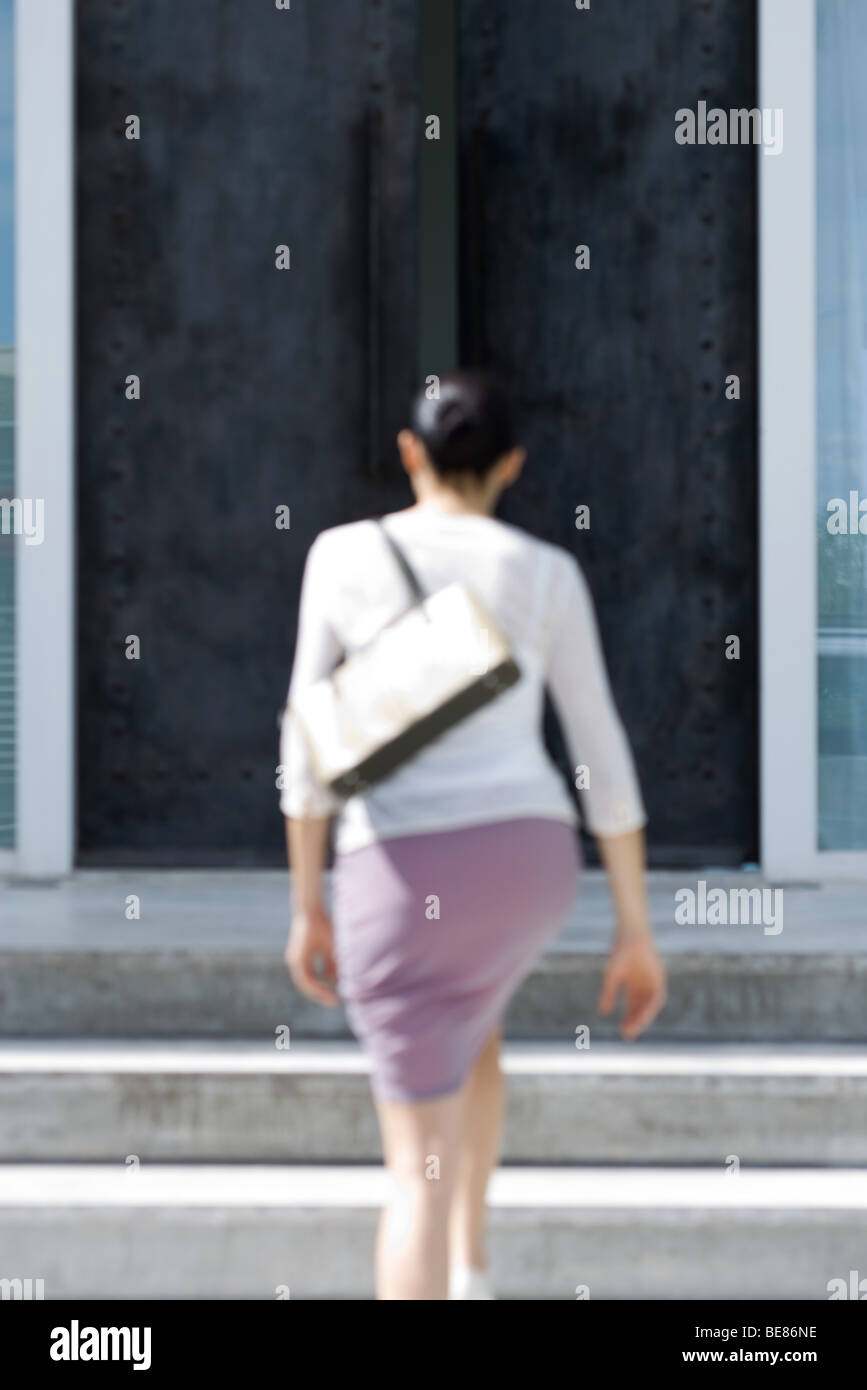 Frau zu Fuß Schritte vor Gebäude, Rückansicht, unscharf gestellt Stockfoto