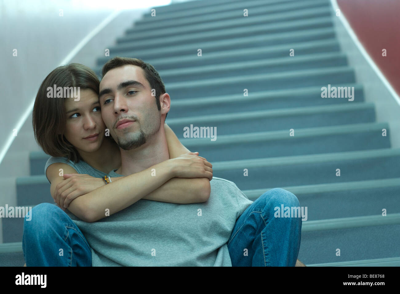 Junges Paar sitzen zusammen auf Treppen, weiblich männlich von hinten umarmen Stockfoto