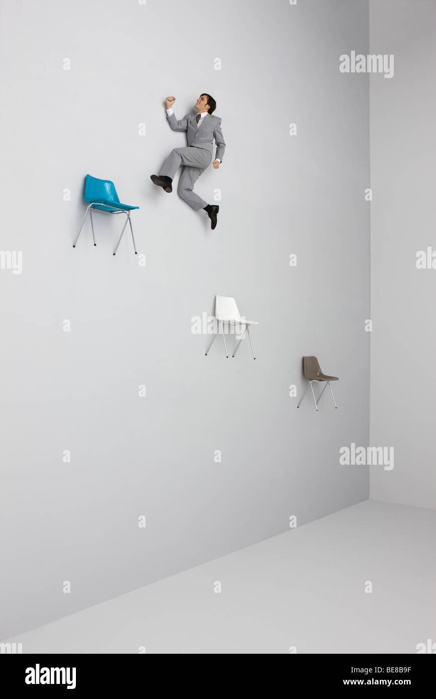 Geschäftsmann, die Luft von Stuhl zu Stuhl springen Stockfotografie - Alamy