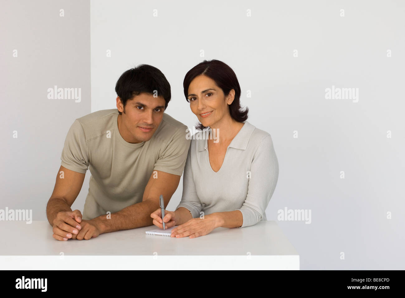 Mutter und erwachsener Sohn zusammen mit Notizblock, Frau schreiben Stockfoto