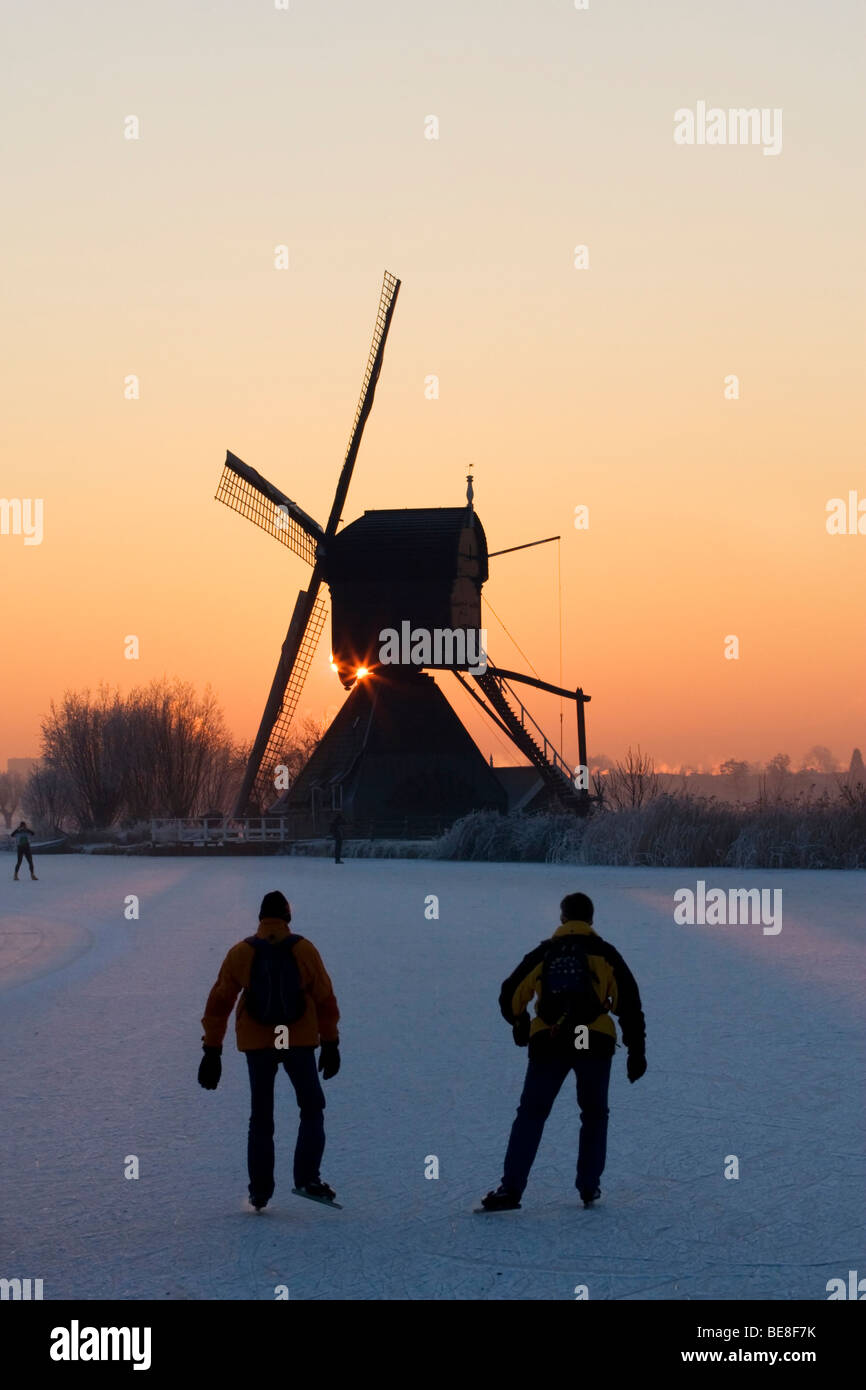 Schaatsers Schaatsen Langs de Molens van Kinderdijk; Eisläufer Skate entlang der Windmühlen von Kinderdijk Stockfoto