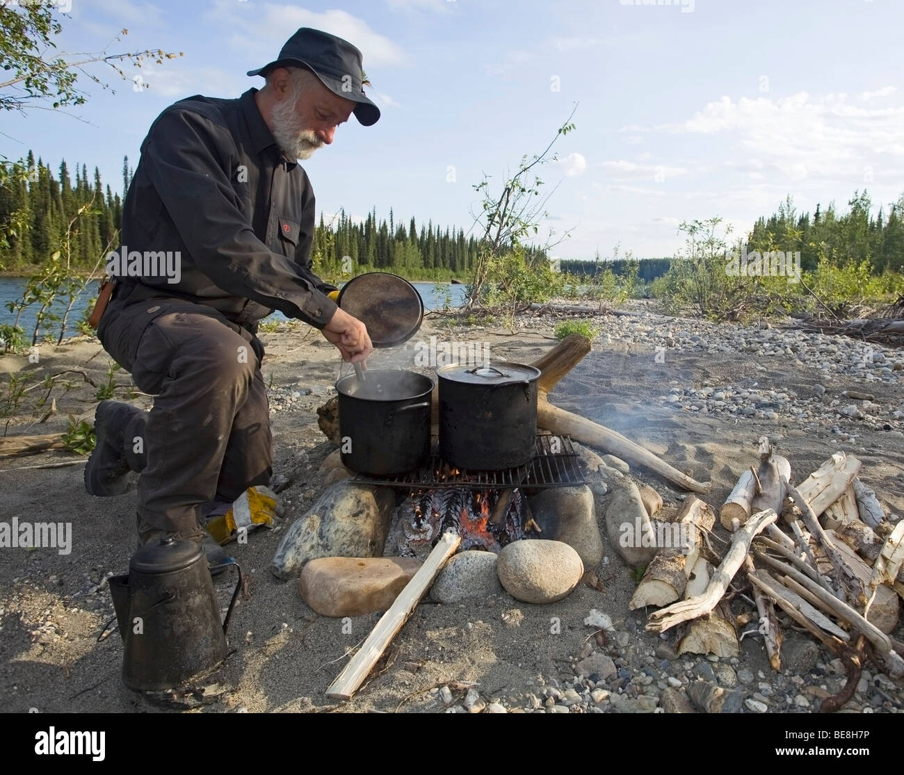 Mann, Kochen am Lagerfeuer, Töpfe, Wasserkocher, oben Liard River, Yukon Territorium, Kanada Stockfoto