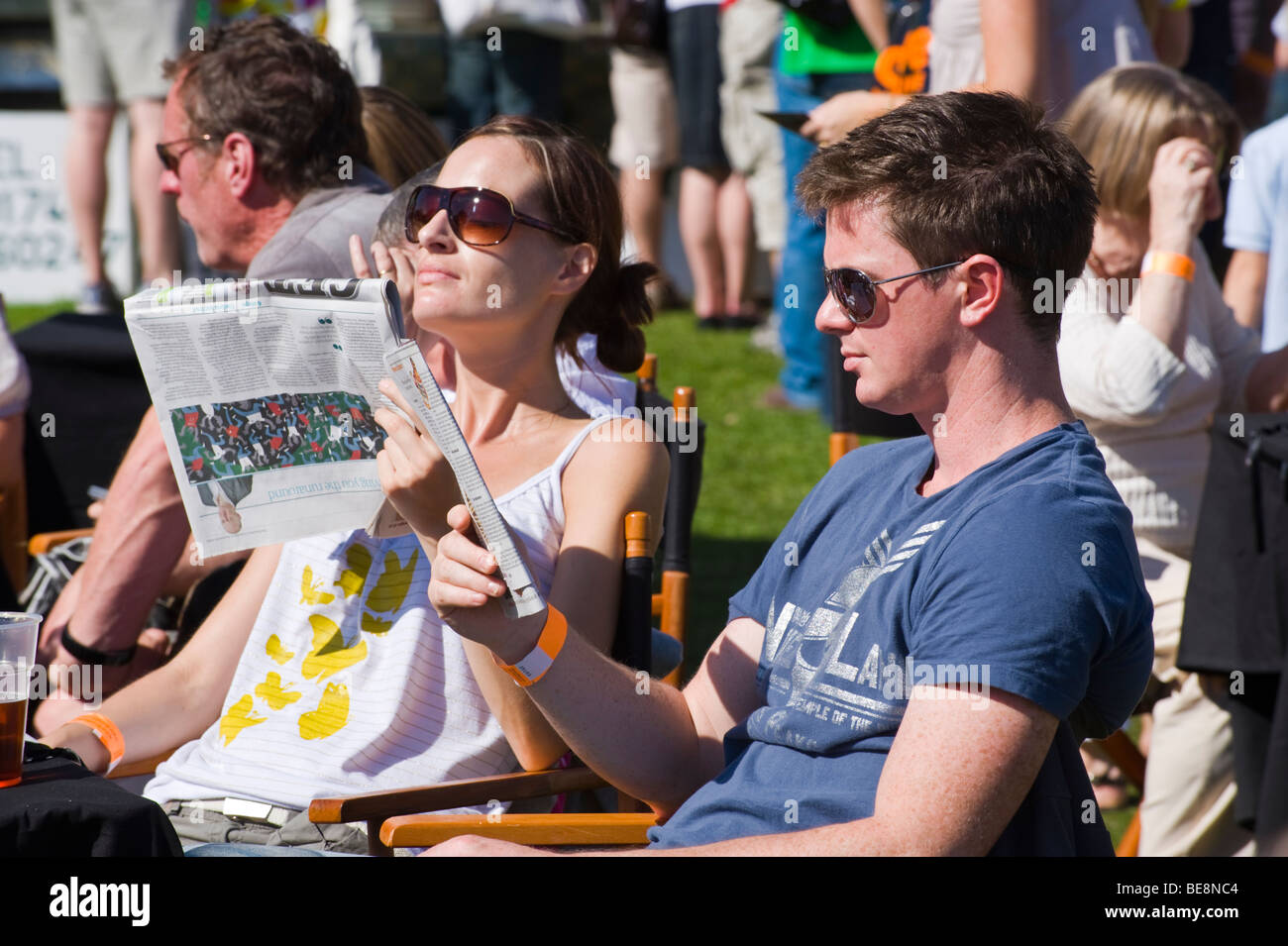 Junges Paar entspannen Lesung im Sonnenschein am Ludlow Food Festival Shropshire England UK Stockfoto