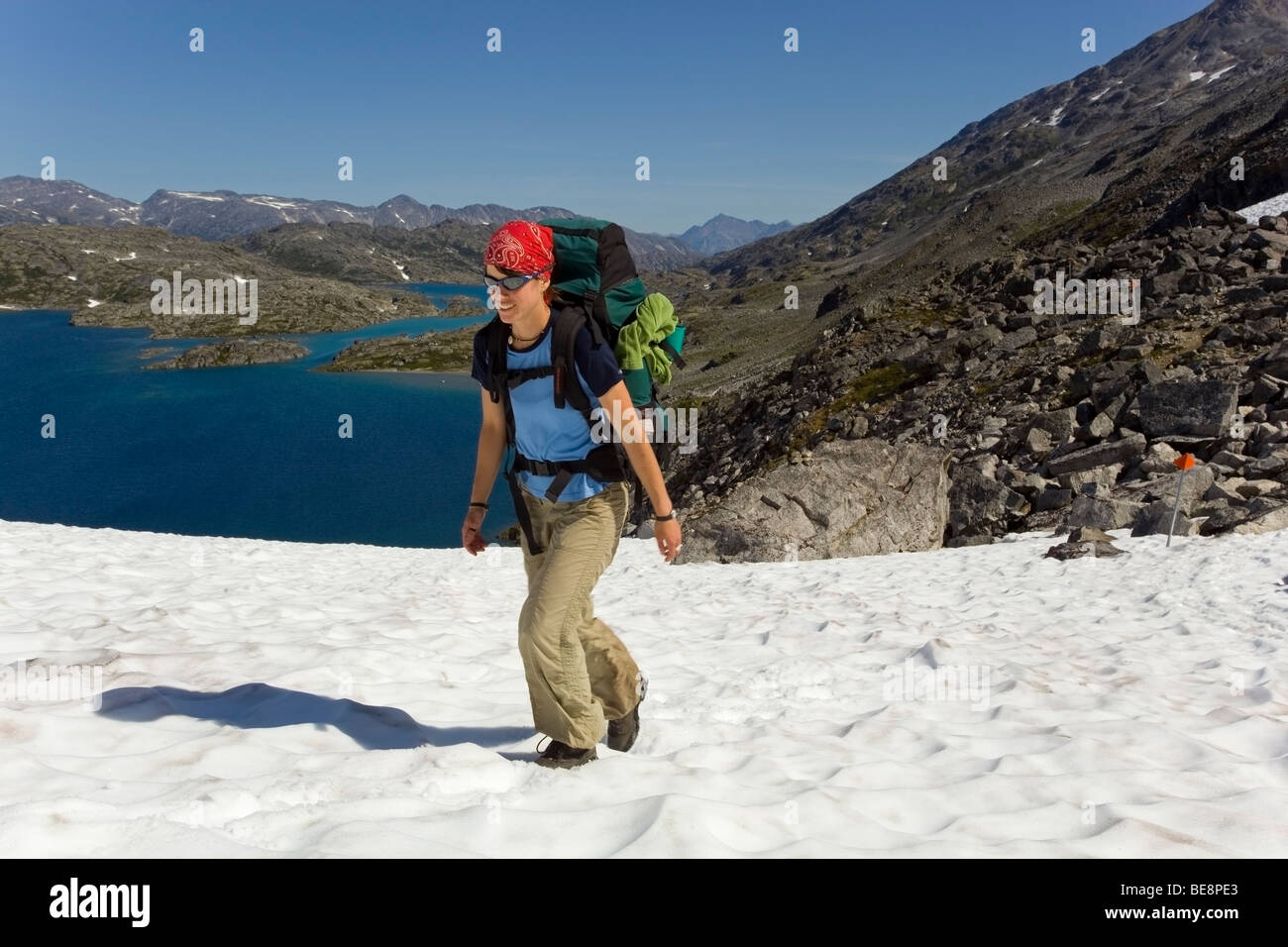 Junge Frau, Wandern, Wandern, Wanderer mit Rucksack, Schneefeld, absteigend in Richtung Gipfel des historischen Chilkoot Trail, Chilkoo Stockfoto