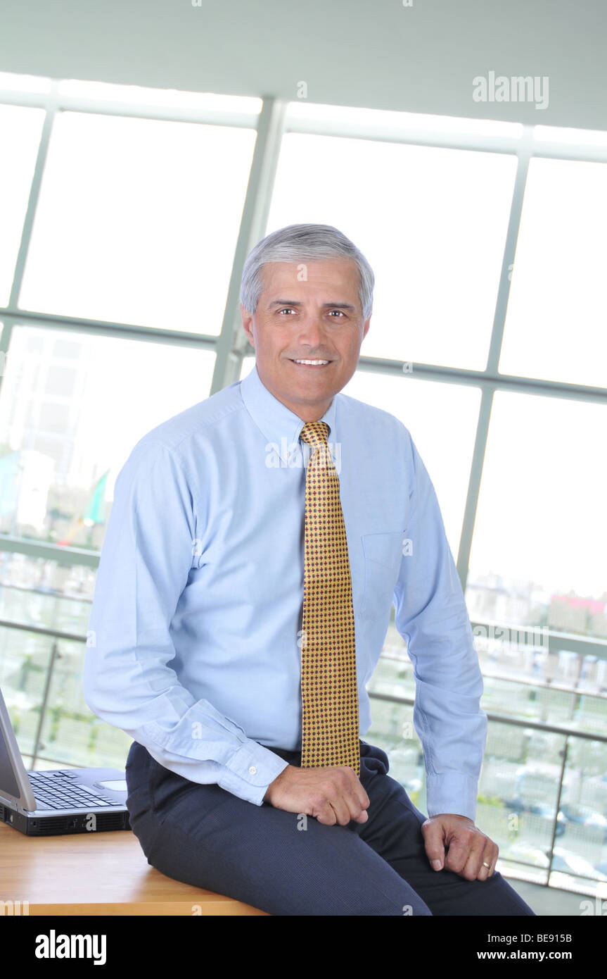 Geschäftsmann am Rande von seinem Schreibtisch im Büro sitzt lächelnd Stockfoto