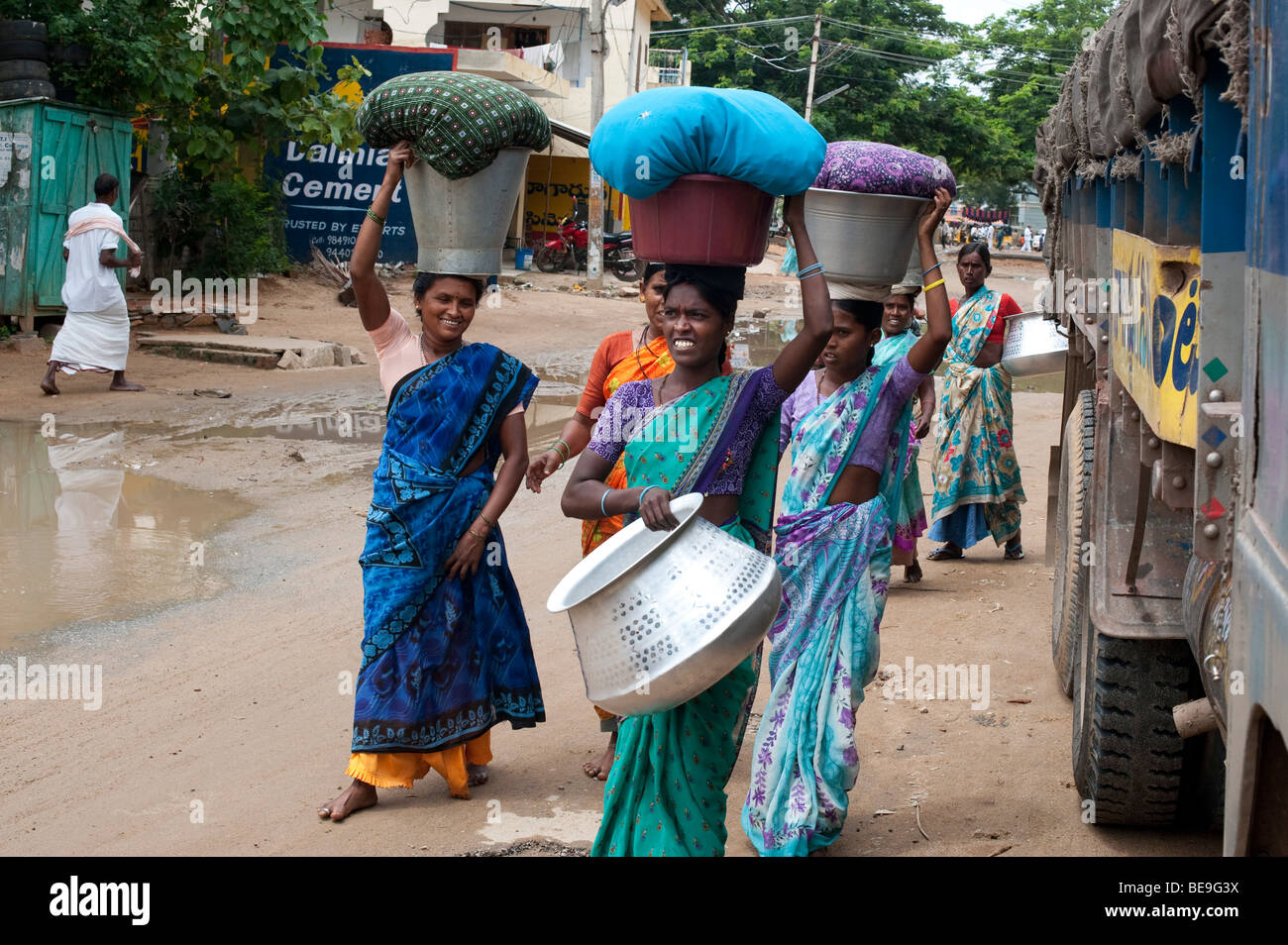 Indische Frauen, die Kleider waschen in Eimer auf es Köpfe durch das Dorf Puttaparthi, Andhra Pradesh, Indien Stockfoto