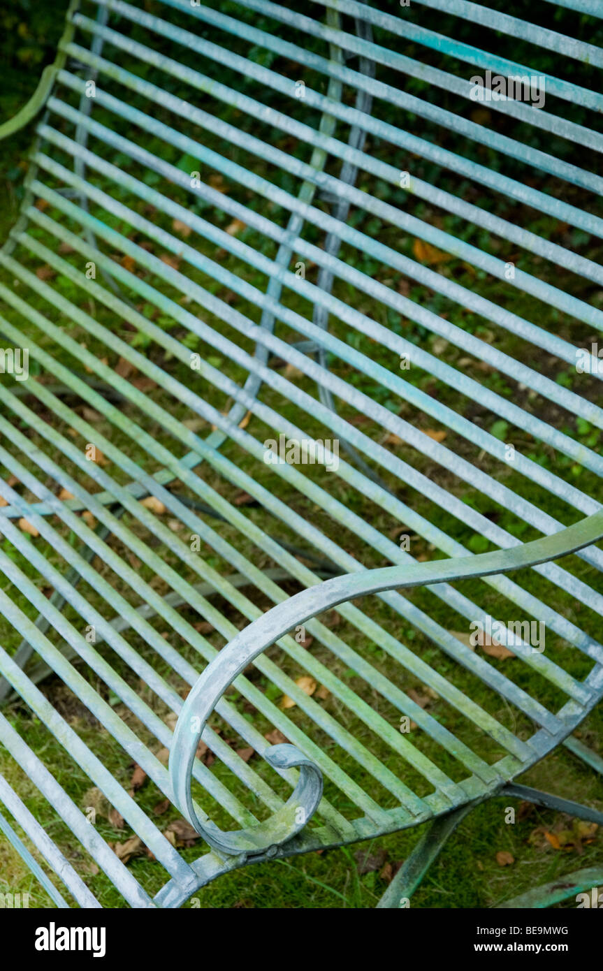 Eine Nahaufnahme, schräg / abstrakt, der eine Gartenbank Schmiedeeisen mit verwitterten, blasse grüne Patina. Stockfoto
