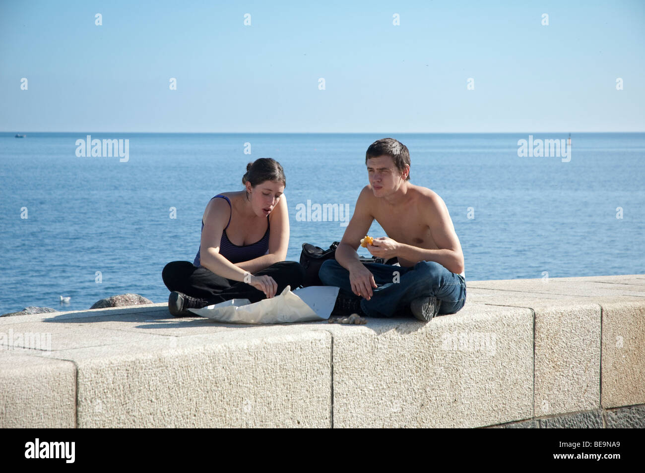 Mann und Frau Essen Fisch und Chips auf dem Deich bei Lyme Regis Stockfoto