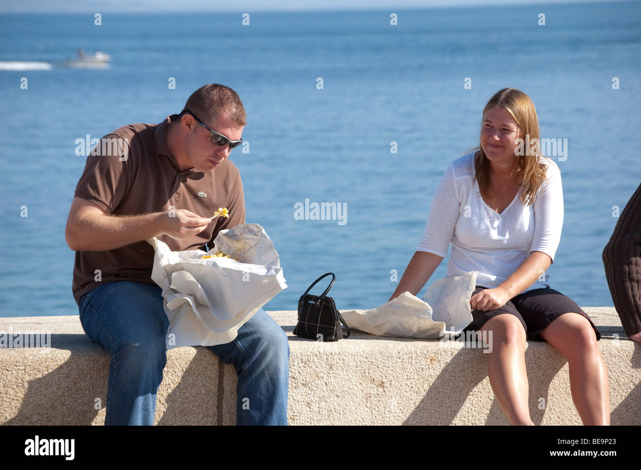 Mann und Frau Essen Fisch und Chips auf dem Deich bei Lyme Regis Stockfoto