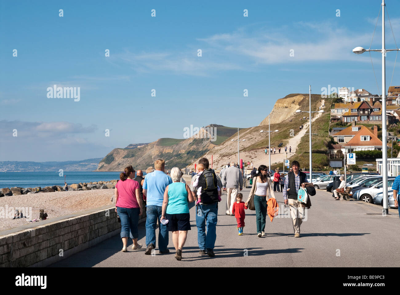 Urlauber zu Fuß entlang der Strandpromenade promenade an der West Bay, Dorset Stockfoto