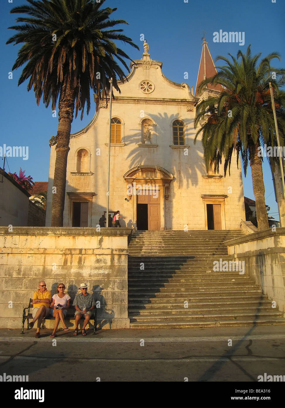 Kroatien; Hrvartska; Fernsehreihe, zentral-Kroatien, Insel Brac, Milna, 2 Männer eine Frau sitzen auf Bank Kirchenmauer Stockfoto