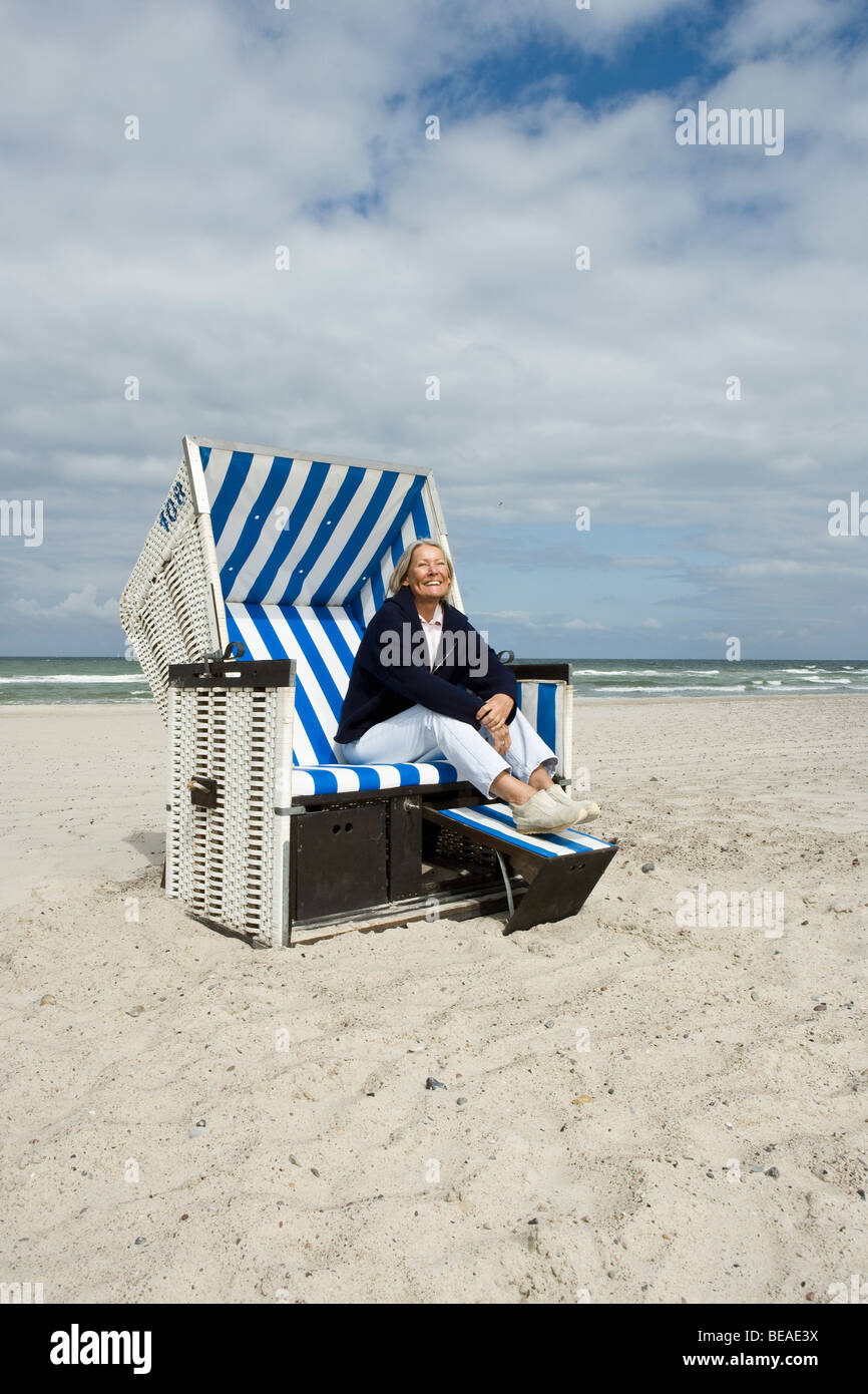 Ein senior Frau sitzt im Strandkorb mit Kapuze Stockfoto