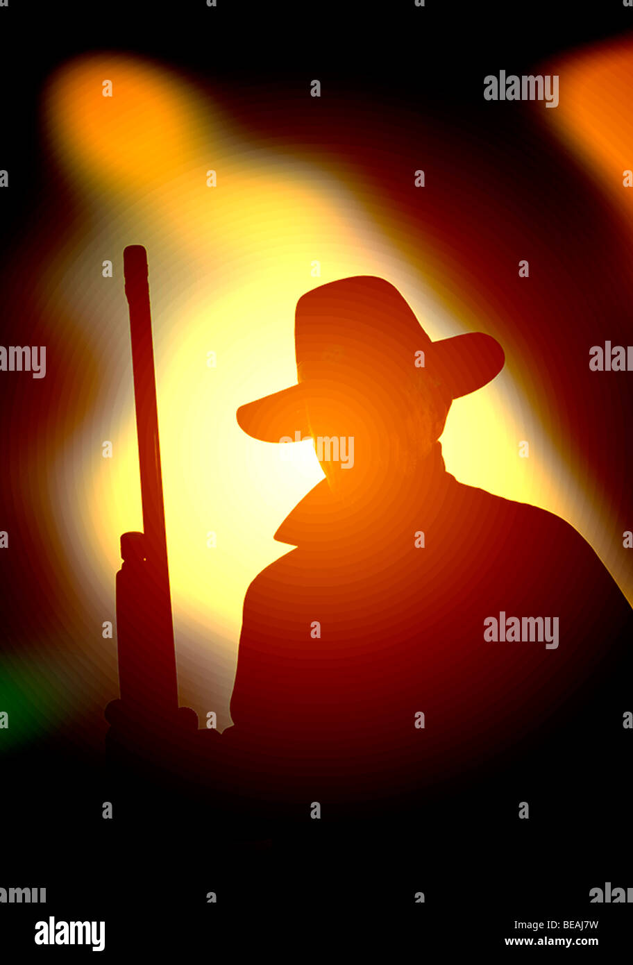 Bösewicht mit Gewehr lauert im Schatten eines Baumes in der Abenddämmerung Stockfoto