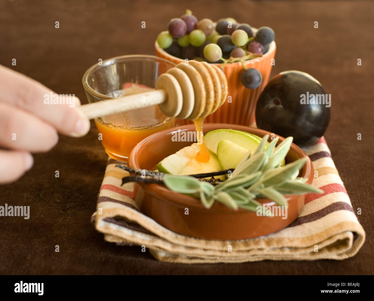 Honig tropft auf eine grüne Apfelscheiben und andere Früchte Stockfoto