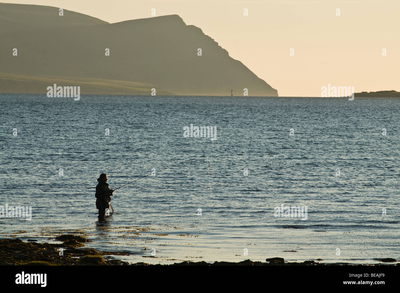 Dh angler angeln SCAPA FLOW ORKNEY Waten fischer Stange off shore Abend Hoy Hills Schottland Stockfoto