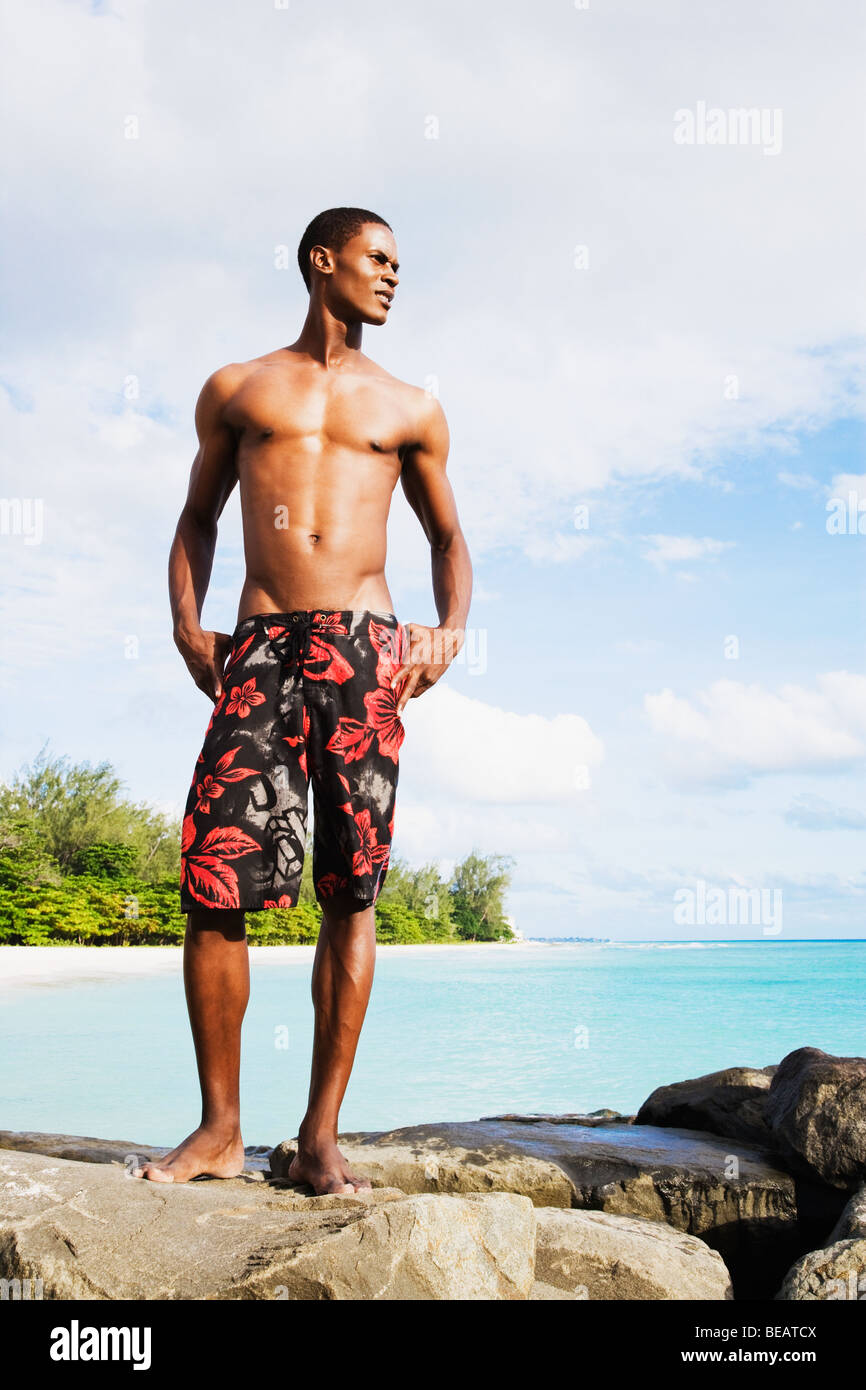 Afrikanischer Mann in Badehose am Felsen vom Ozean Stockfotografie - Alamy