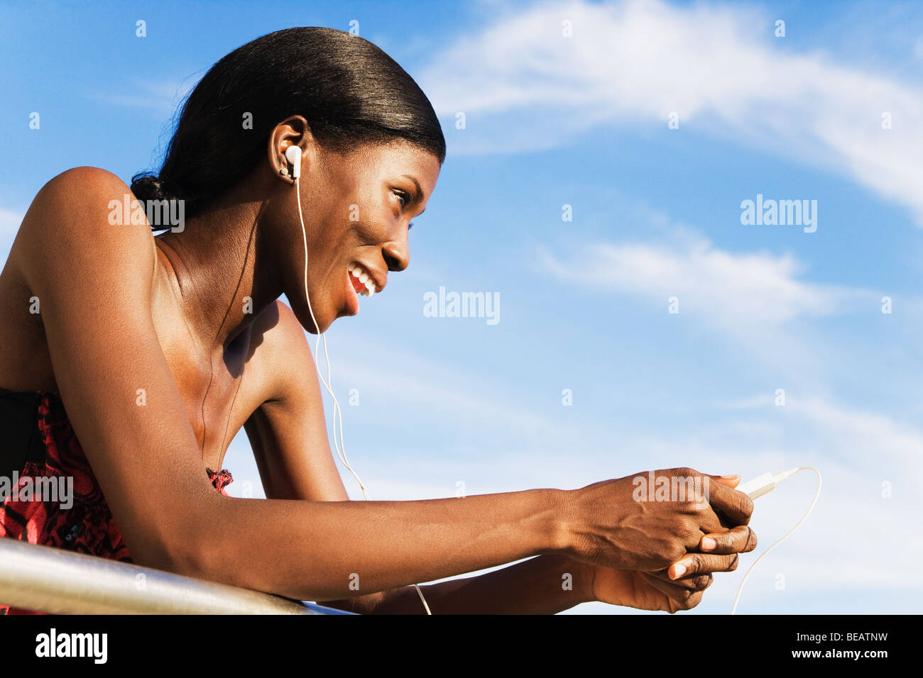 Afrikanische Frau trägt Kopfhörer und Holding MP3-player Stockfoto