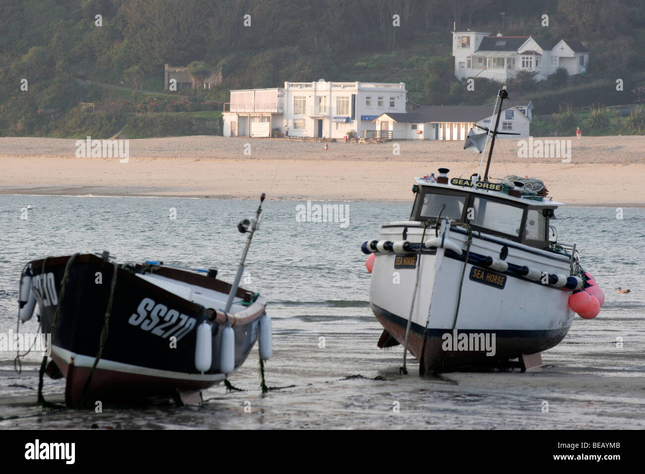 Angelboote/Fischerboote bei Ebbe in St Ives Harbour mit dem Porthminster Café und Strand im Hintergrund Stockfoto