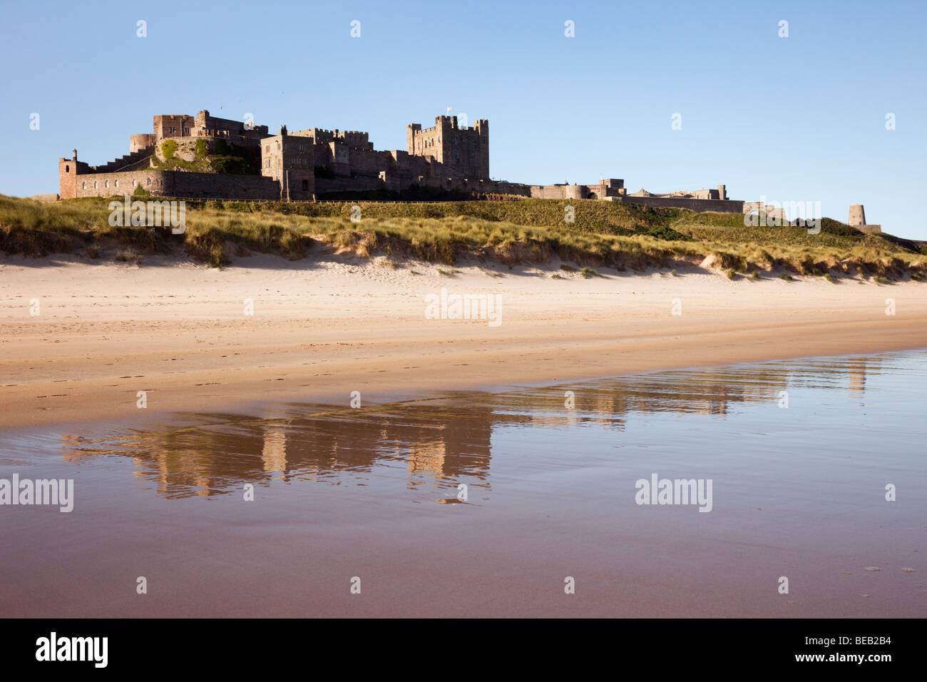 Bamburgh Castle spiegelt sich in den nassen Sand auf leeren Strand Vorland. Bamburgh, Northumberland, England, Großbritannien, Großbritannien Stockfoto