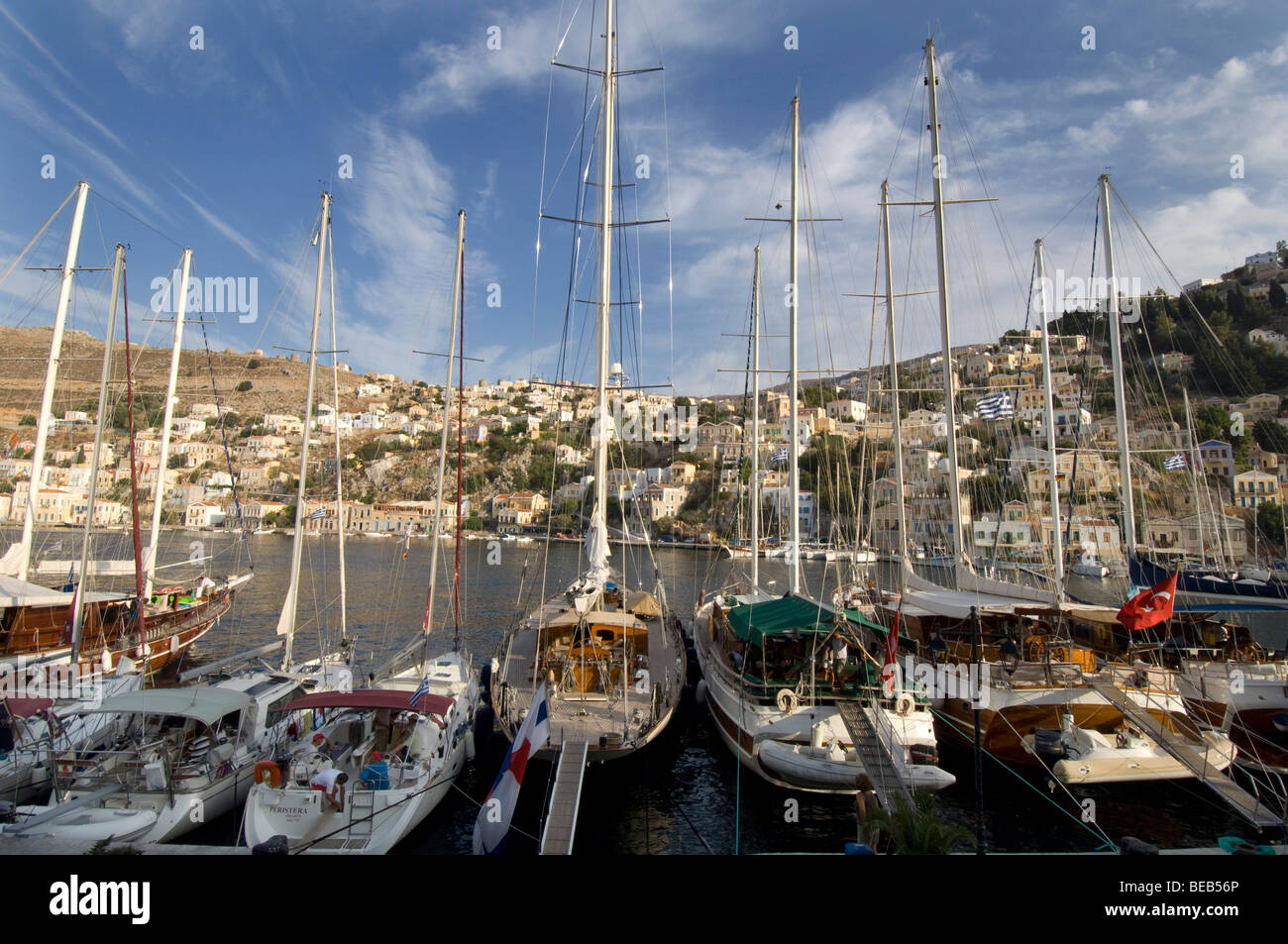 Yachten im Hafen von Yialos auf der griechischen Dodekanes Insel Symi mit den Neo-klassizistischen Häusern der Stadt im Hintergrund. Stockfoto