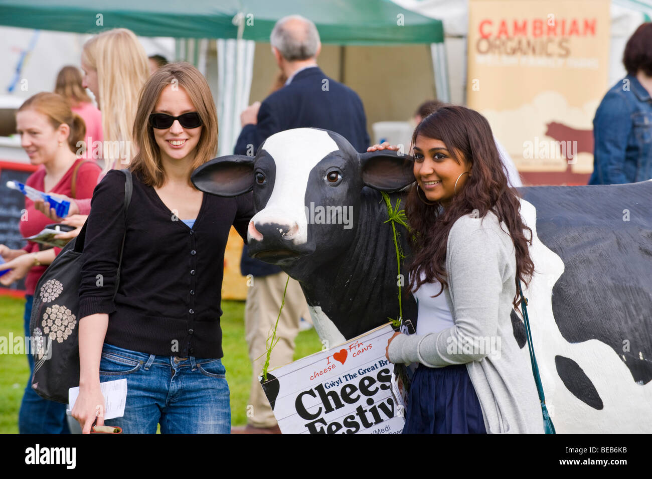Zwei junge Frauen haben ihr Foto mit Werbe Kunststoff Kuh an der großen britischen Käse Festival Cardiff South Wales UK Stockfoto