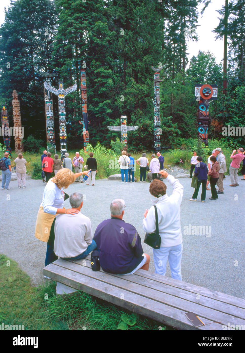 Touristen an Totempfähle, Stanley Park, Vancouver, BC, Britisch-Kolumbien, Kanada - Brockton Point, Sommer Stockfoto