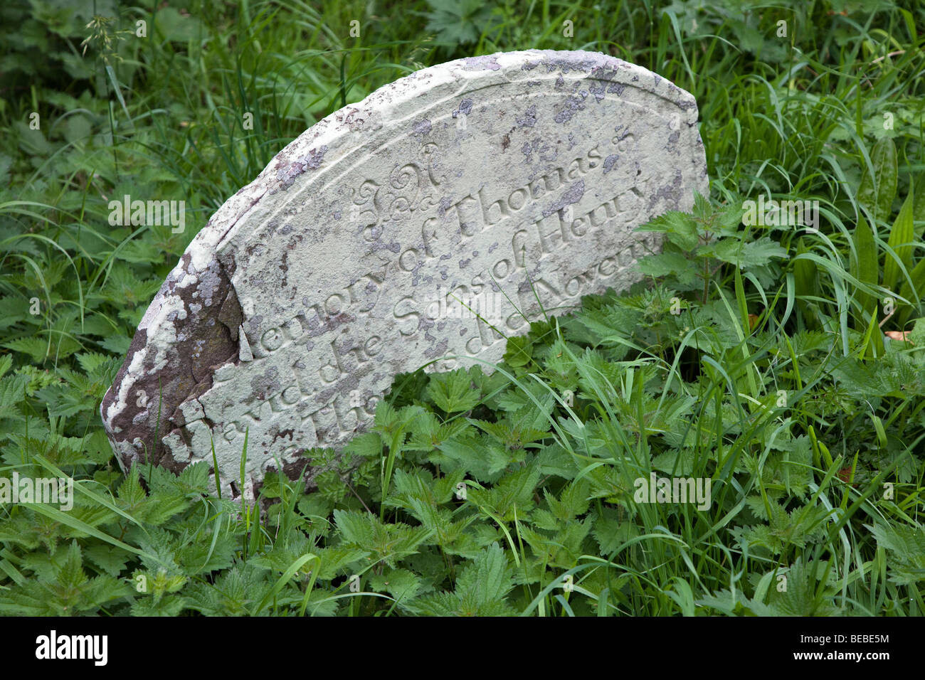 Verwitterter Grabstein und Schuppen mit Inschrift bedeckt in Flechten überwucherten Friedhof Wales UK Stockfoto