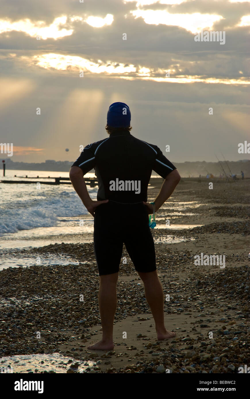 Eine Silhouette des männlichen Triathlet am Strand stehen und blickte auf einen dramatischen Himmel Stockfoto