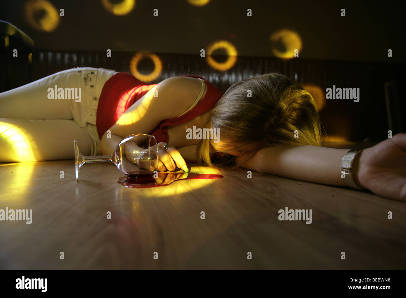 Betrunkenes Mädchen liegend mit Hochdruck daran einen Nachtclub Stock mit einem klopfte Weinglas und verschüttete Wein. Stockfoto