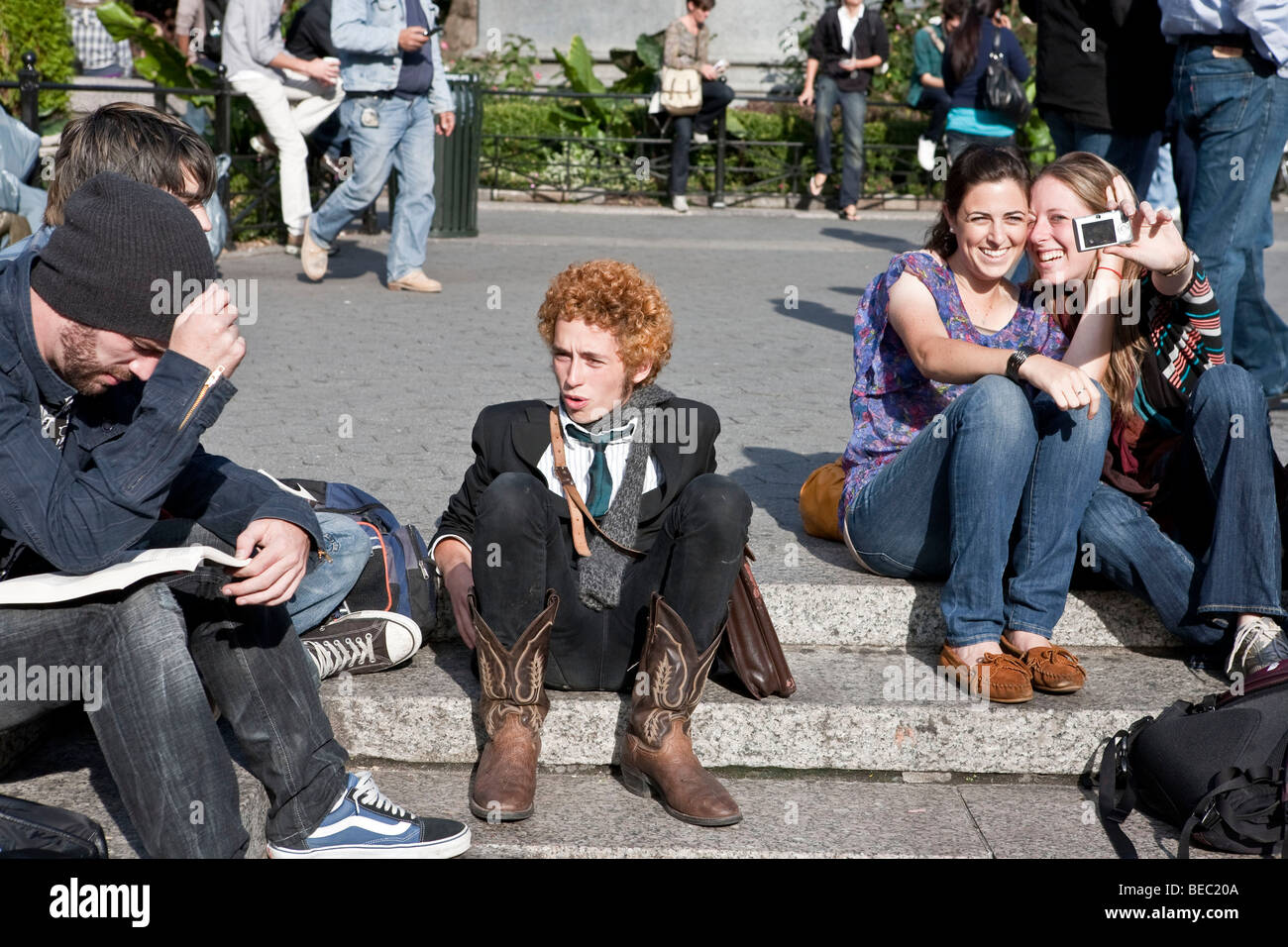 junges Publikum von Menschen genießen, lesen, entspannen & schnappen Fotos in einem sonnigen Union Square Park New York City Stockfoto