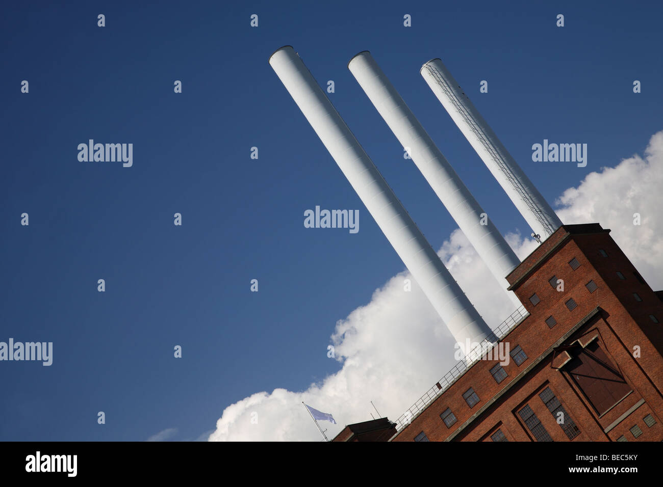 Kraftwerk mit drei Schornsteinen symbolische Gewehrläufe schussbereit vor blauem Himmel mit weißen Wolken bilden. Stockfoto